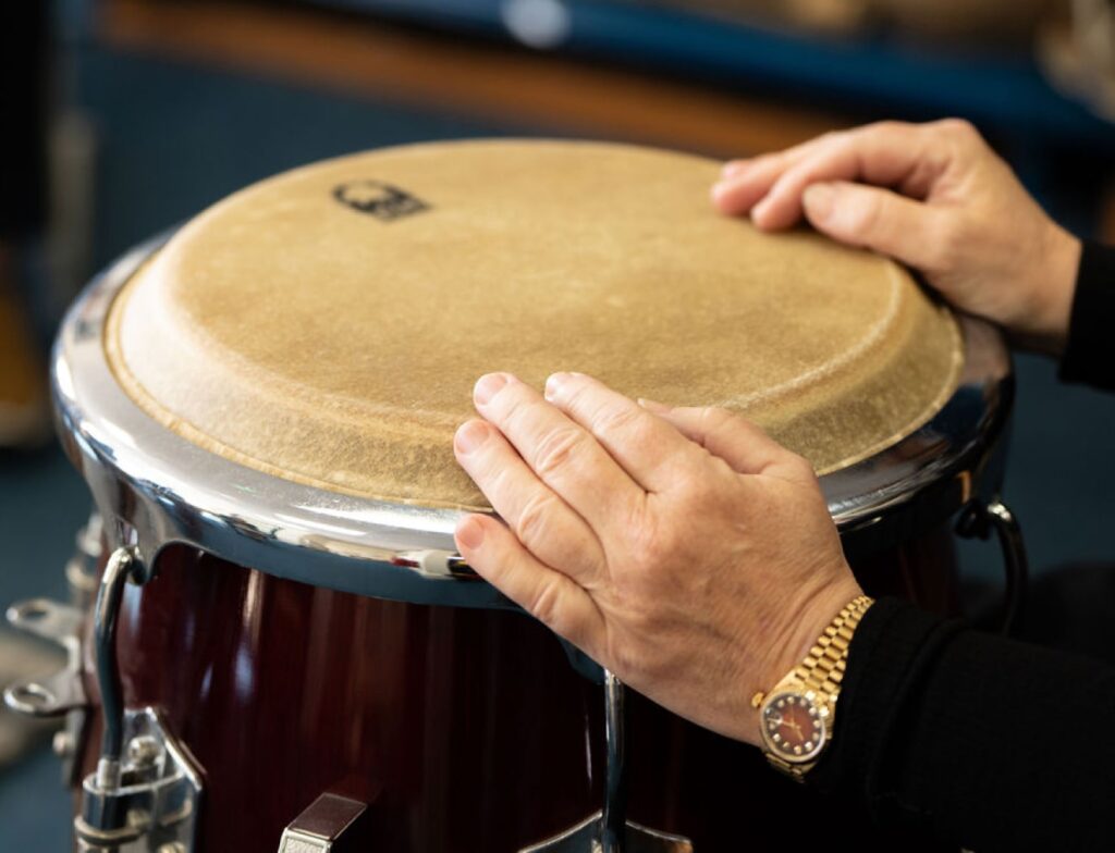 Evelyn's hands rest on a Conga during a 'Who's Listening' workshop.