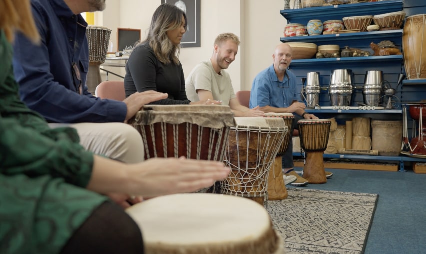 Enthusiastic participants play Djembes as part of a 'Who's Listening' workshop.