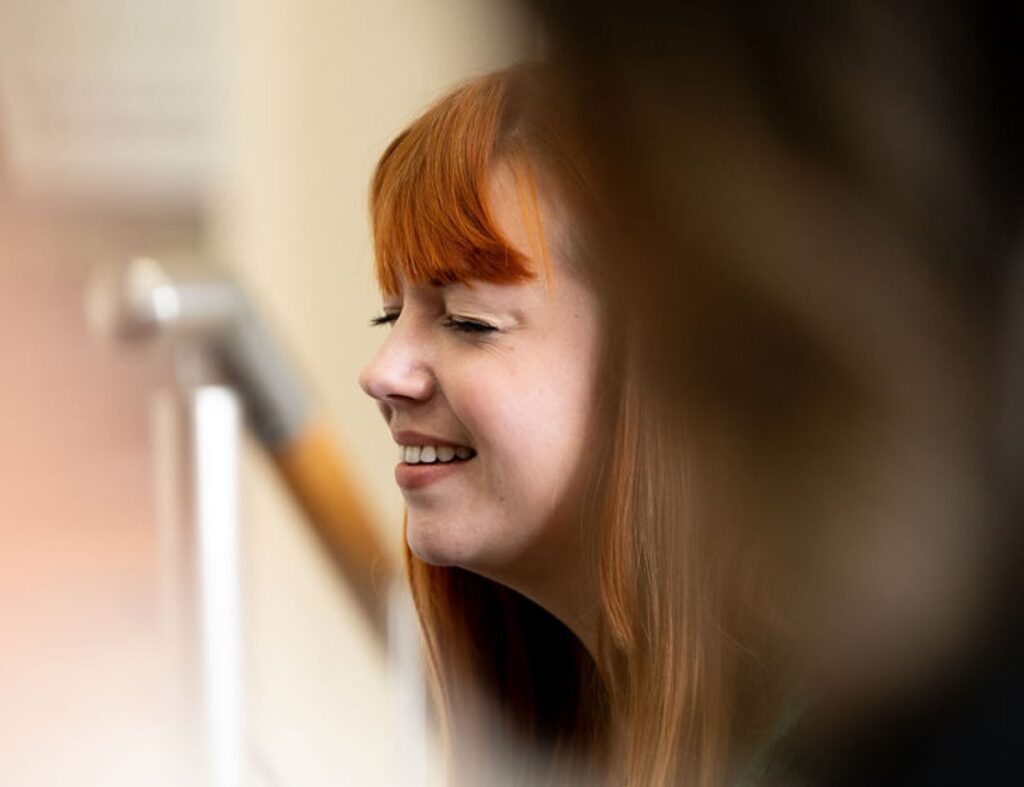 A striking photo of a young, red-headed woman, as she takes part in a 'Who's Listening' workshop.