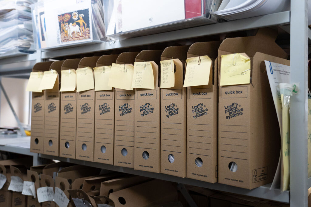 Some grey shelves from the Archive room, which houses many of the documents from The Evelyn Glennie Collection. This photo features a row of brown archive boxes.